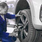 Mechaniker arbeitet am Rad eines Fahrzeugs auf der Hebebühne