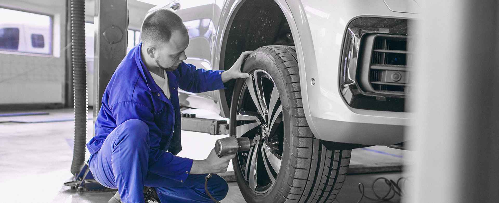 Mechaniker arbeitet am Rad eines Fahrzeugs auf der Hebebühne
